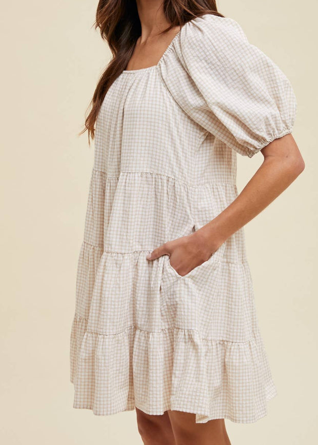 Woman wearing a white checkered dress against a beige background