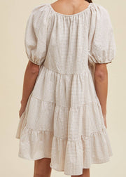 Checkered dress with puff sleeves on a beige background